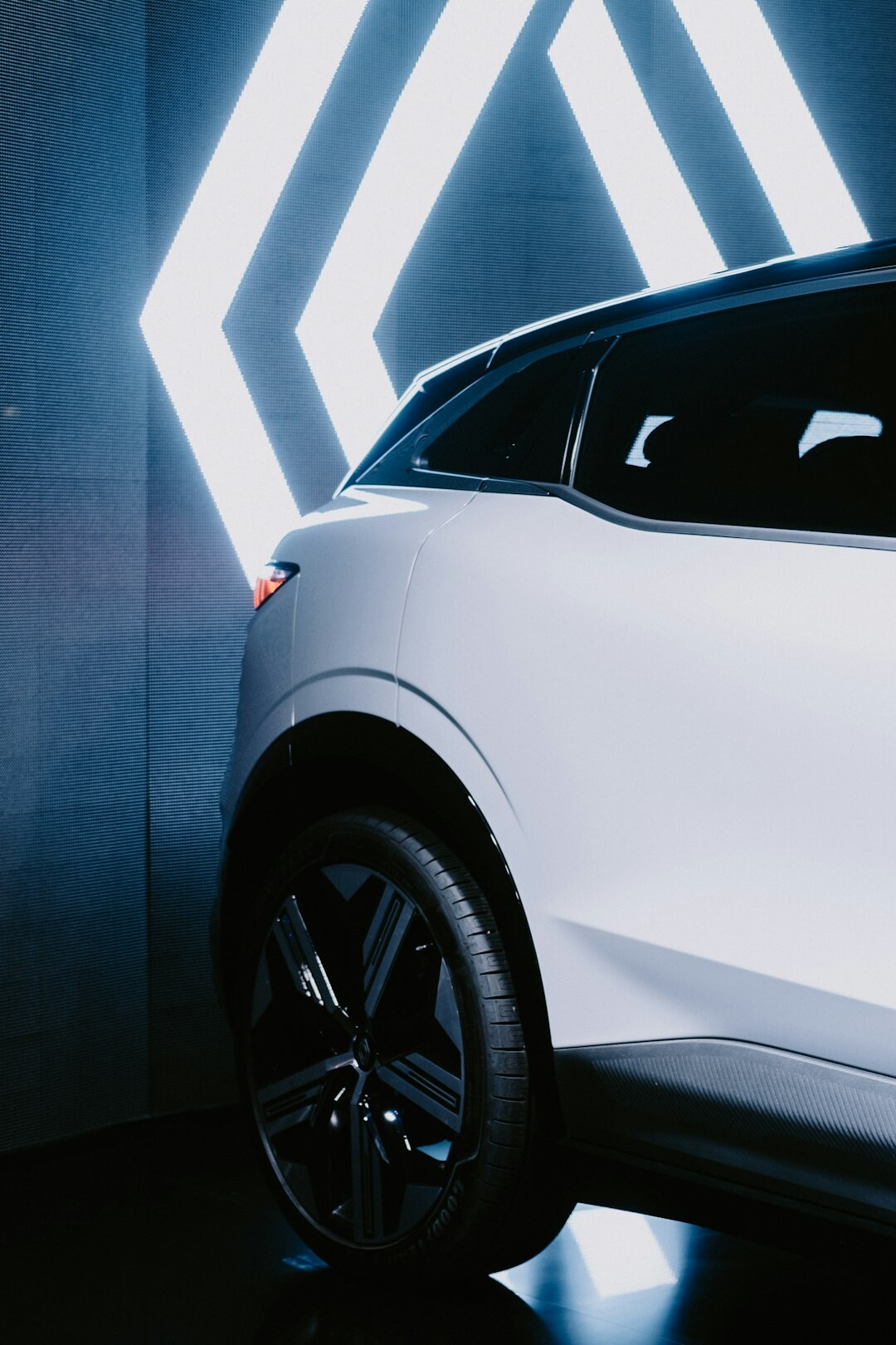 White electric SUV photographed in a futuristic studio