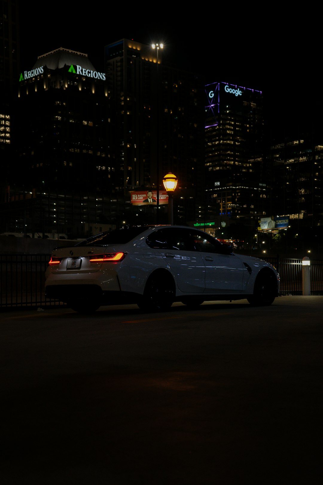 Dark grey premium sedan photographed at night with city lights